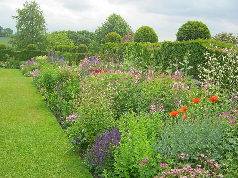 A long double herbaceous border in full summer flower beside a lawn path